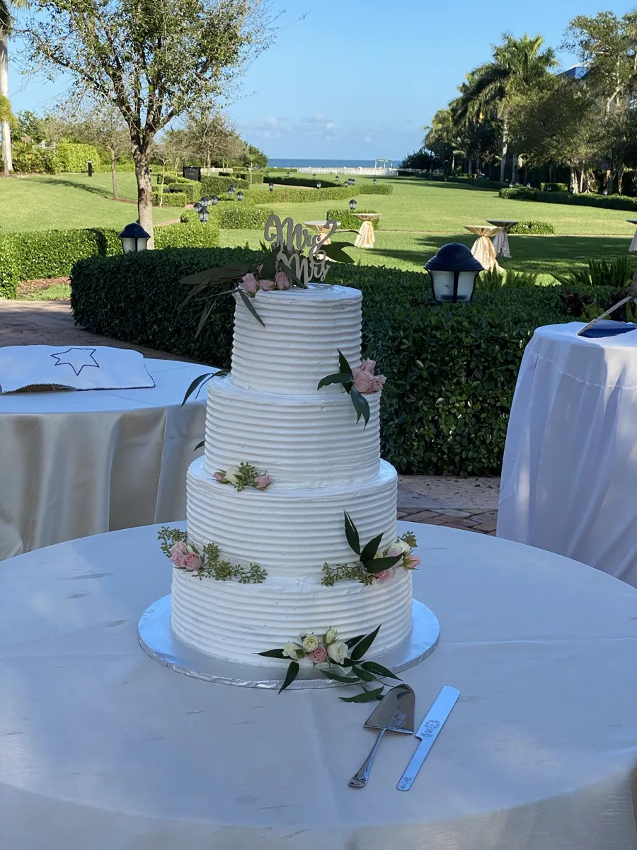 Four-tier buttercream wedding cake with fresh flowers and Mr and Mrs topper
