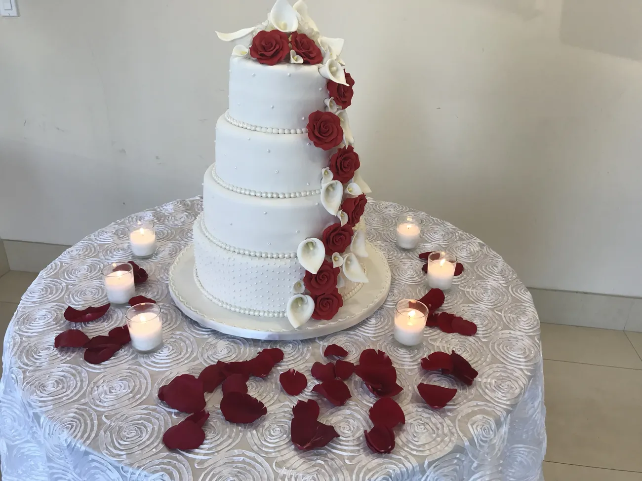 Four-tier fondant wedding cake with red sugar roses and white calla lilies
