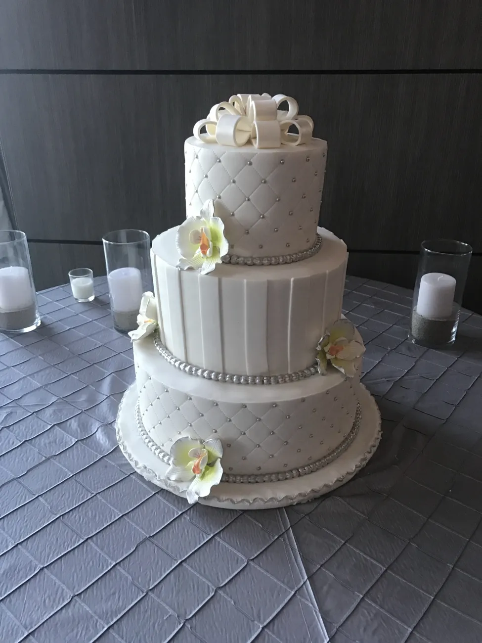 Three-tier quilted fondant wedding cake with sugar orchids and bow