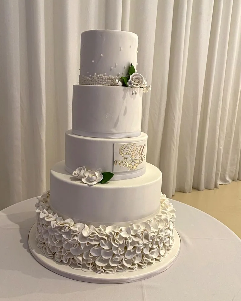 Custom four-tier wedding cake with sugar florals and monogram