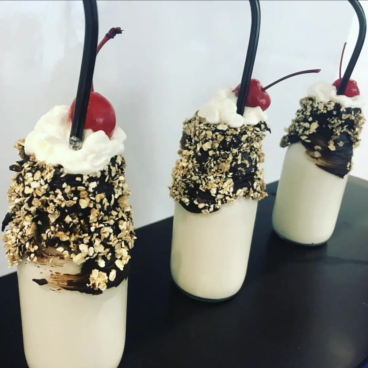 Milkshakes with chocolate and oat rim, whipped cream and cherry